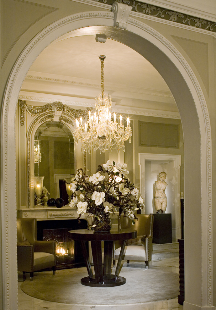 arched-doorway-chandelier-round-table-flower-arrangement-fireplace-seating-area 01
