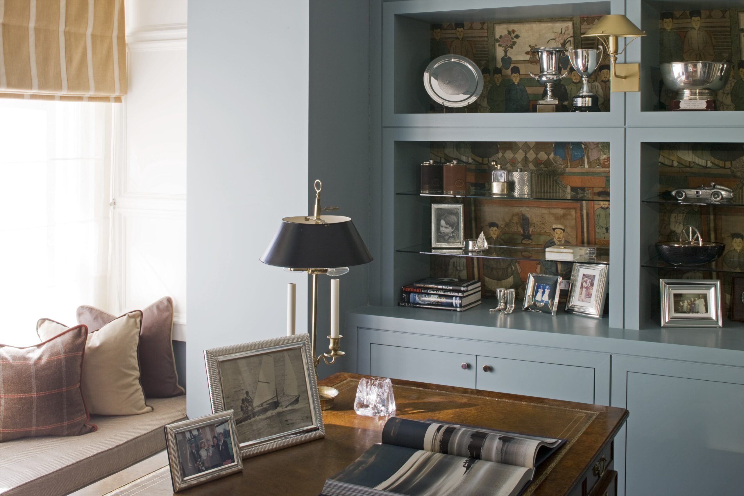 blue-built-in-shelving-desk-table-lamp-framed-photos-window-blind-home-office 06